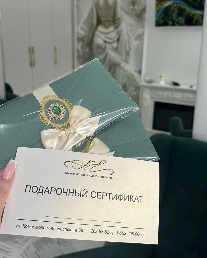 Сертификат в конверте и карточка с адресом и телефоном клиники на фоне холла